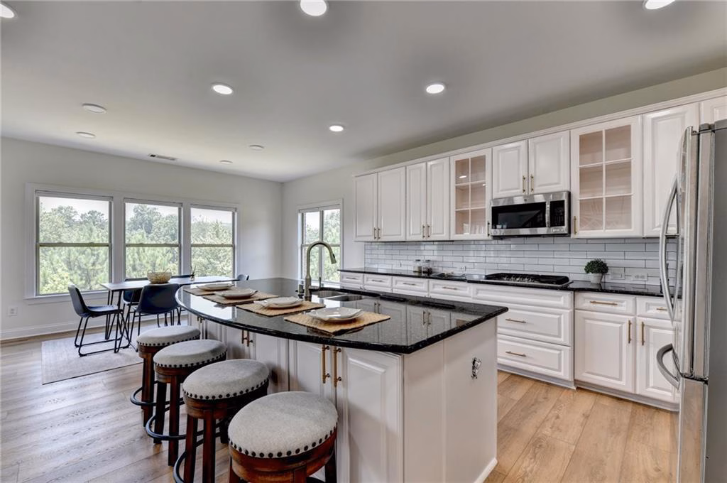 Main kitchen with a large dark-topped island, white cabinetry and wooded outlook